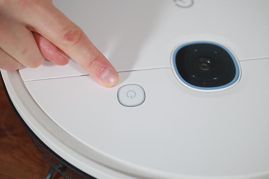 Der Steuerungsknopf des Yeedi Vac Saugroboters wird mit einem Finger angeklickt